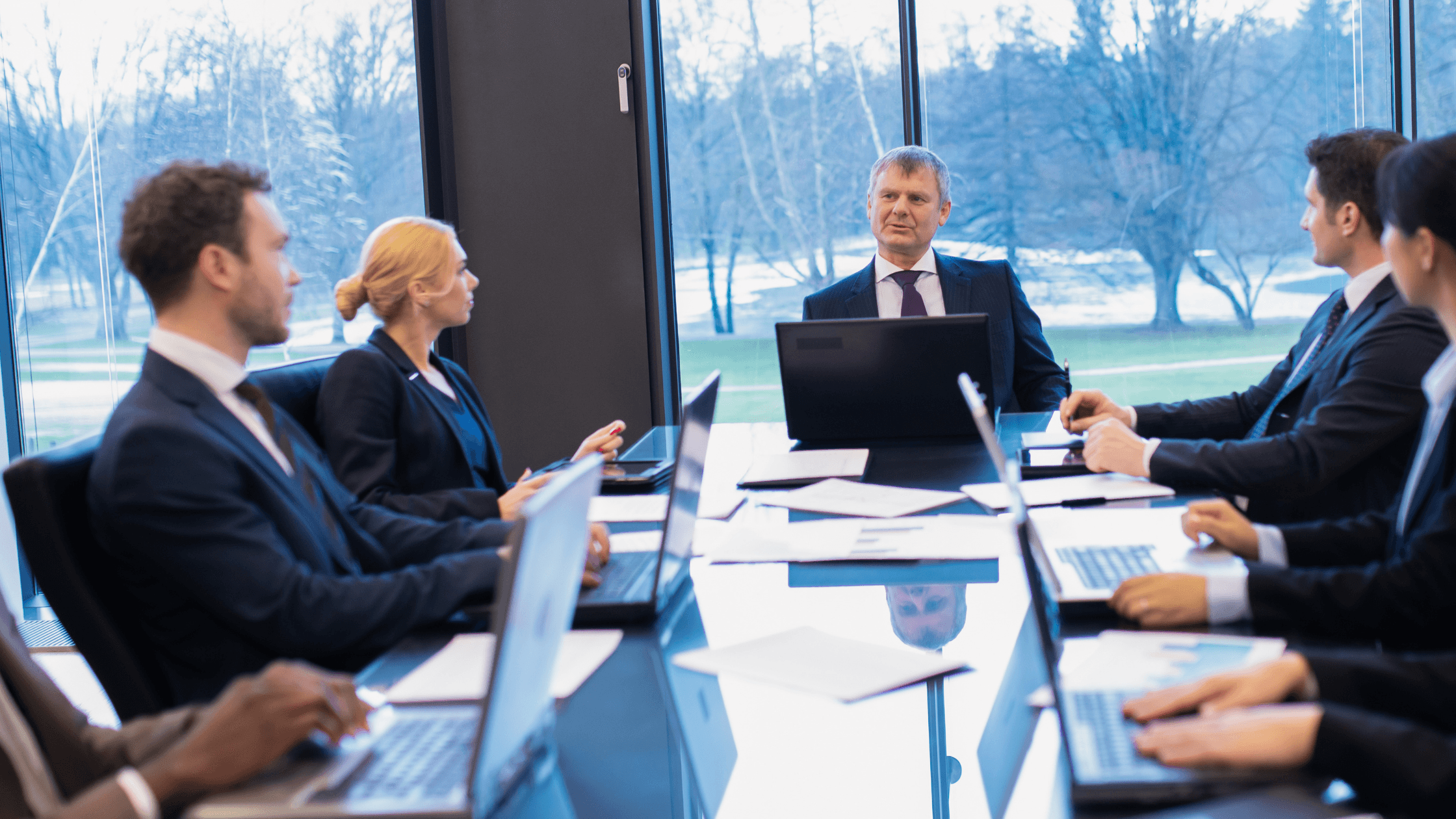 business people in conference room with laptops open, having a discussion